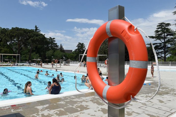 Archivo - Varias personas se bañan y toman el sol en una piscina municipal.