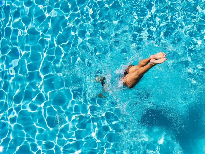 Mujer lanzándose a la piscina en verano.