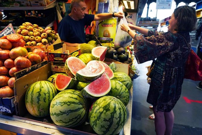 Varias personas compran fruta en el mercado de Atarazanas donde la sandía ha tenido una subida de precios por la falta de lluvias y encarecen el precio de una de las frutas más demandadas en época estival a 3 de agosto de 2023 en Málaga, Andalucía