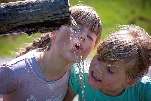 Archivo - Niñas beben agua de una fuente.