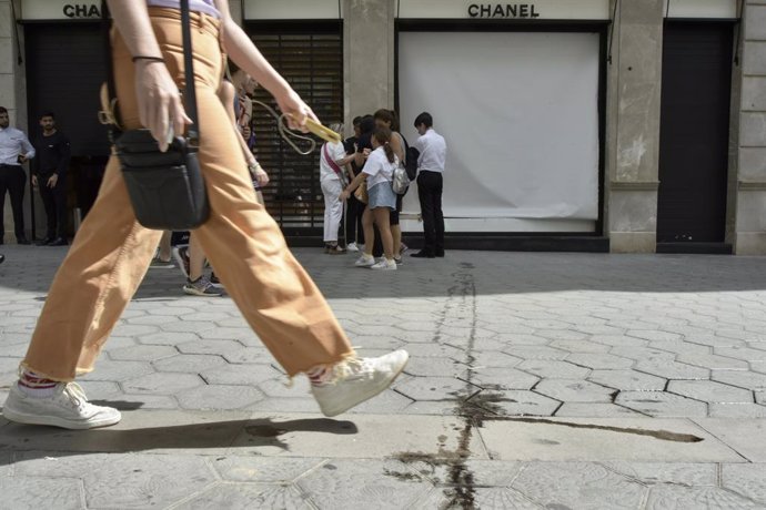 Diverses persones caminen enfront de l'aparador de la botiga de Chanel que ha sofert aquesta matinada un intent de robatori, a 7 d'agost de 2023, a Barcelona, Catalunya (Espanya).