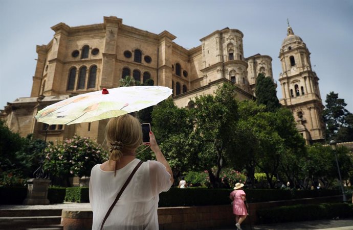 Una señora con un paraguas fotografía la Catedral durante la ola de calor que estos días azota la capital a 19 de julio e 2023 en Málaga, Andalucía. La Agencia Estatal de Meteorología (Aemet) ha activado para este miércoles el aviso rojo por altas tempe