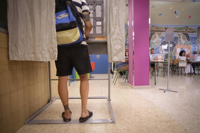 Una persona con indumentaria playera se prepara para ejercer su derecho a voto durante las elecciones generales, en el Colegio Público N1, a 23 de julio de 2023, en Foz, Lugo, Galicia (España). 