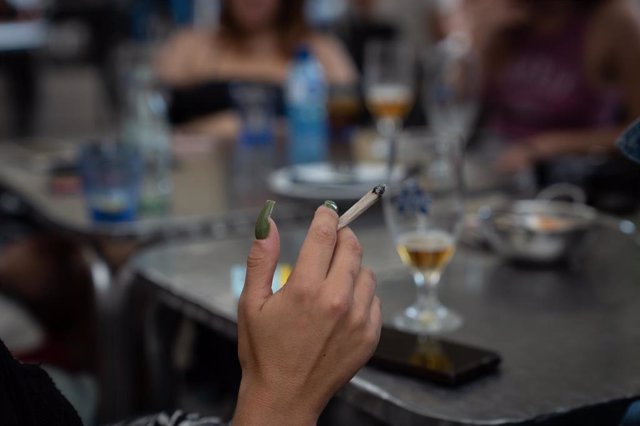 Archivo - Una mujer fuma sentado en la mesa de una terraza