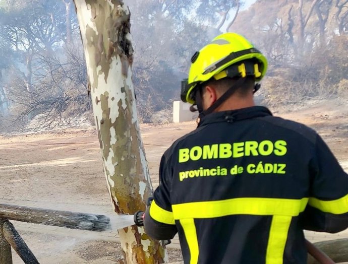 Un bombero del Consorcio de Bomberos de la Provincia de Cádiz actuando para sofocar un incendio declarado este martes en El Puerto (Cádiz)