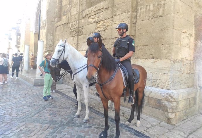 Archivo - Policías locales a caballo atienden a turistas junto a la Mezquita-Catedral de Córdoba.