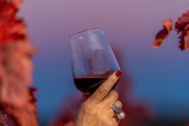 Mujer bebiendo una copa de vino tinto.