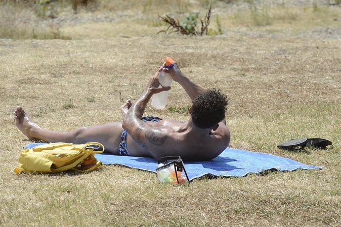 Archivo - Un hombre toma el sol en la zona piscinas de Oira, a 12 de julio de 2022, en Orense