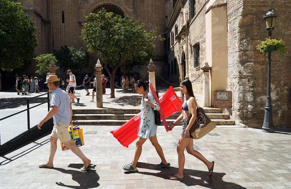 Varias personas intentan protegerse de las altas temperaturas que azotan estos días la capital malagueña 