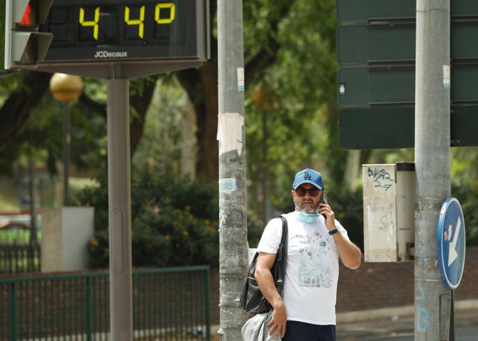 Archivo - Un hombre habla por el móvil junto a un termómetro que marca 44 durante un día de alerta roja por altas temperaturas, a 12 de julio de 2021, en la ciudad de Murcia, Murcia (España). Las provincias de Alicante, Valencia y Murcia tienen este lu