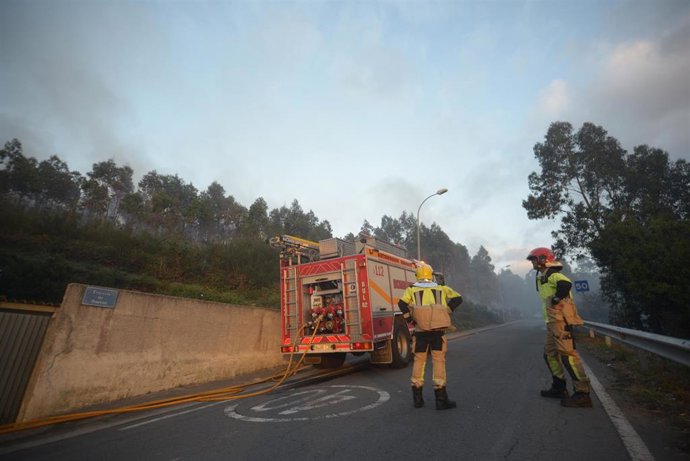 Bomberos trabajan para extinguir el fuego en un incendio forestal en Arteixo.