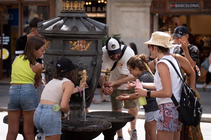 Varias personas se refrescan y rellenan sus botellas de agua en la fuente de Canaletas, en Barcelona