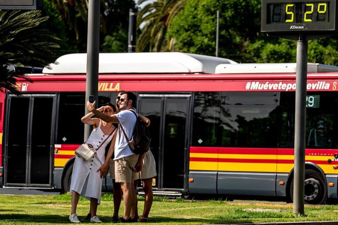 Turistas se hacen una fotos detrás de un termómetro que marca 52 grados, en plena hora de calor, a 07 de agosto del 2023 en Sevilla (Andalucía, España). La Agencia Estatal de Meteorología (Aemet) ha activado este martes el aviso naranja por altas temper