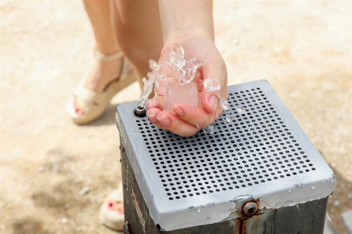 Una mujer se refresca en una fuente 