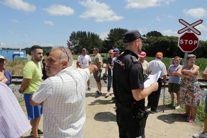 Un agente de Policía Nacional al lado de los vecinos de las parroquias de Coeo y Recimil durante una concentración 
