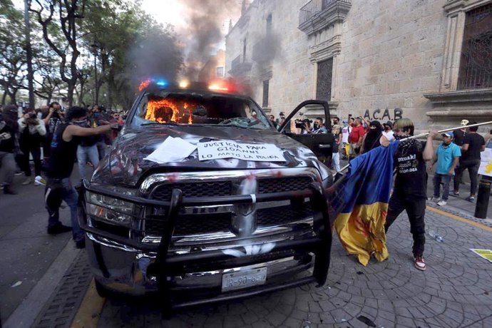 Archivo - Escena de Caos en México, con un coche de policía incendiado.