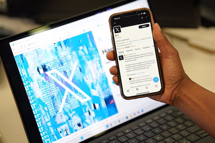 24 July 2023, United Kingdom, London: A person looks at the new logo for Twitter on an Apple iPhone in an office in London. Twitter has replaced the social media platform's famous bird logo with an X as part of owner Elon Musk's plans to create an "ever