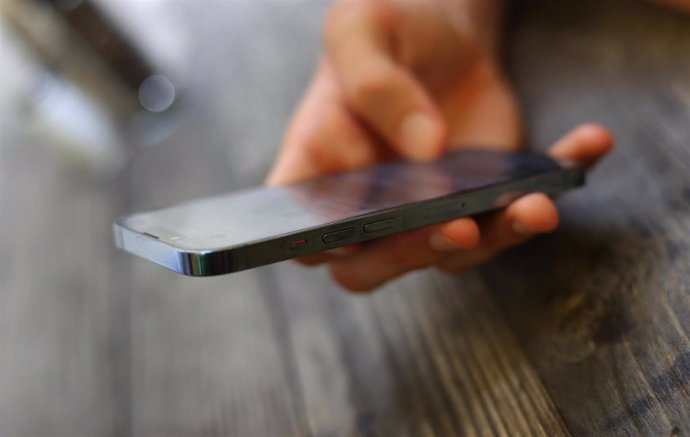 Archivo -  A young man holds a smartphone.