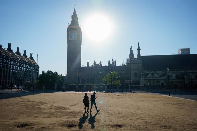 Archivo - 13 August 2022, United Kingdom, London: Two people cross parched grass on Parliament Square, Westminster, as a drought has been declared for parts of England following the driest summer for 50 years. Photo: Dominic Lipinski/PA Wire/dpa