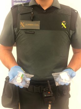 Un agente sostiene dos bolsas con la droga intervenida al pasajero.