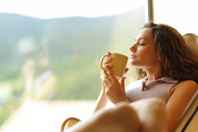 Mujer tomando un café descansando junto a una ventana.