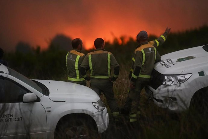 Varios agentes de emergencias observan el incendio forestal, a 18 de agosto de 2023, en Palas de Rei, Lugo, Galicia (España). El incendio forestal, que se ha iniciado la tarde de hoy y se ha visto avivado por el viento, ronda, según la Consellería de Me