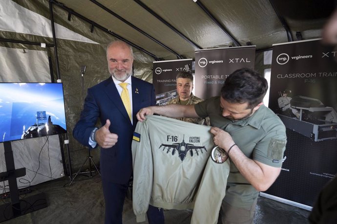 August 6, 2023, Kyiv, Kiev Oblast, Ukraine: Ukrainian President Volodymyr Zelenskyy, right, is presented with a fighter pilots jacket with the logo of the F-16 Fighting Falcon aircraft while visiting the flight simulation training system provided by the