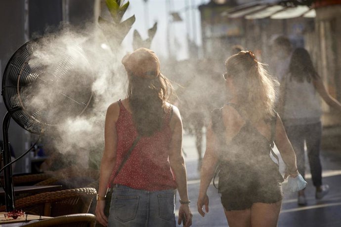 Archivo - Varias personas caminan al lado de un difusor de vapor de agua de un restaurante de la calle Alcalá, a 2 de julio de 2021, en Madrid, (España).
