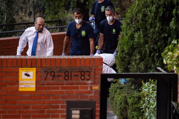 Varias personas sacan uno de los cadáveres del domicilio en el que fueron encontrados, a 17 de agosto de 2023, en Madrid (España).