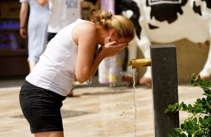 Una mujer se refresca en una fuente en Valencia