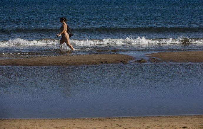 Archivo - Una chica en bikini se pasea por la orilla de la playa