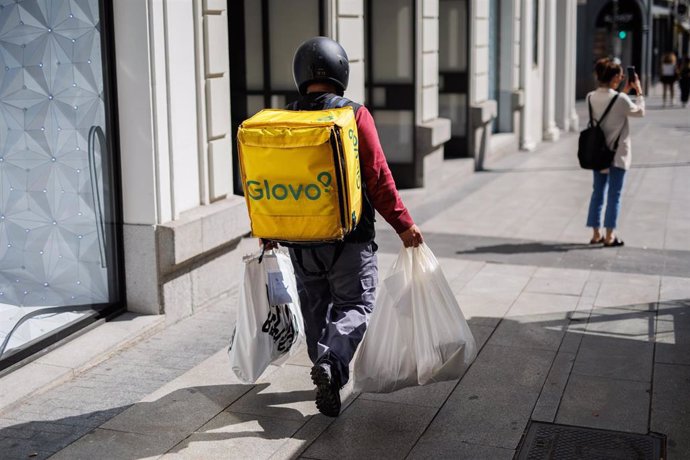 Archivo - Un repartidor de Glovo con bolsas camina por una calle del centro de Madrid 