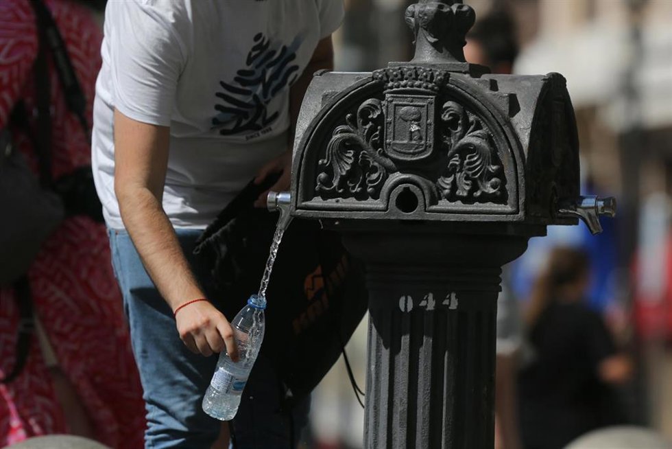 Archivo - Una persona coge agua de una fuente, foto de archivo