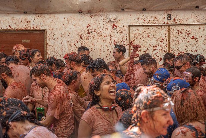 Archivo - Varias personas cubiertas de tomate participan en la festividad de la Tomatina