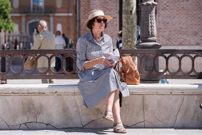 Archivo - Una mujer mayor se protege del sol con sombrero y gafas en la plaza de Cervantes, a 23 de abril de 2023, en Alcalá de Henares, Madrid