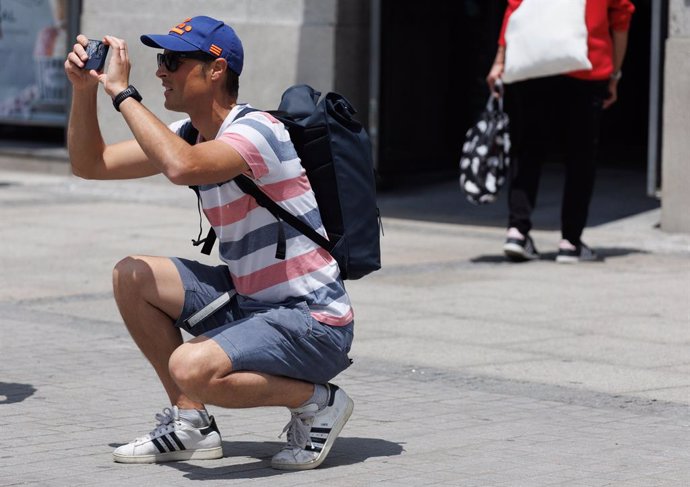 Archivo - Un turista toma fotografías en la Puerta del Sol, a 1 de junio de 2023, en Madrid (España).  