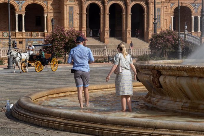 Turistas se refrescan en la fuente de la Plaza de España en Sevilla, en imagen de archivo. 