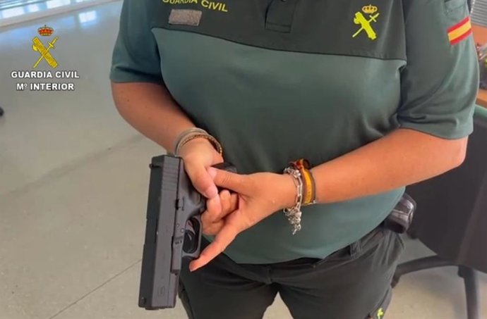 Un agente de la Guardia Civil con la pistola simulada intervenida a la banda de ladrones de viviendas desarticulada en Ibiza