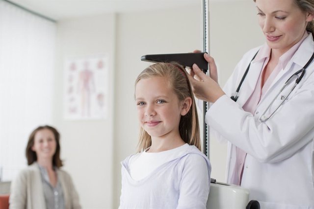 Médica mide la estatura de una niña.