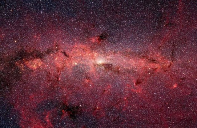 El centro de la Vía Láctea en luz infrarroja, visto por el Telescopio Espacial Spitzer. Un estudio reciente muestra menos tipos de planetas más comunes en las afueras de nuestra galaxia.