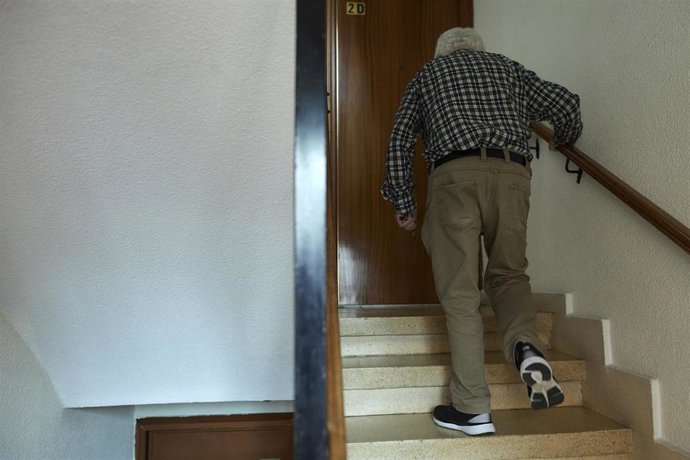 Archivo - Un señor de 78 años sube las escaleras del portal de su vivienda 
