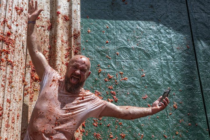Archivo - Un hombre posa cubierto de tomate, durante la festividad de la Tomatina