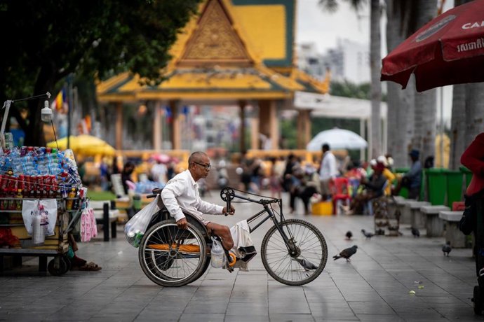Archivo - Una persona pasa con una bicicleta adaptada para discapacitados en Nom Pen, Camboya