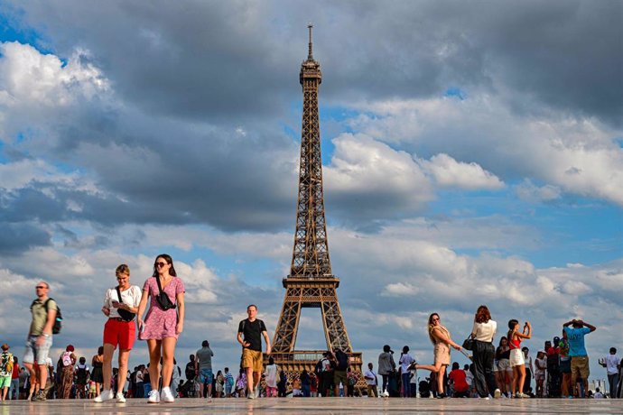 16 August 2023, France, Paris: People walk by the Eiffel Tower, the symbol of the city. One person has been arrested after a parachute jump from the Eiffel Tower. Photo: Miguel Medina/AFP/dpa