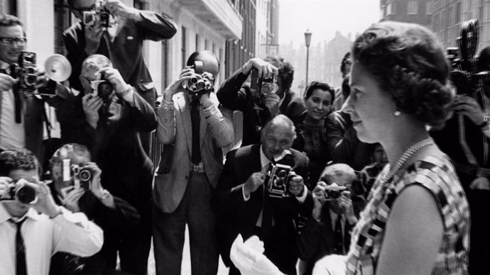 La Reina Isabel II siendo fotografiada por múltiples cámaras.