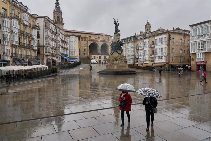 Archivo - Dos personas se refugian con un paraguas de la lluvia en Vitoria. 