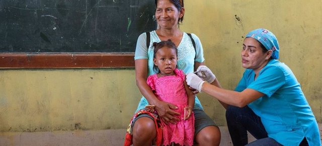 Archivo - Una niña de dos años recibe la vacuna contra la gripe en un dispensario móvil de Loreto, Perú.