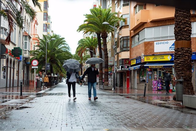 Archivo - Dos personas se refugian de la lluvia bajo un paraguas en una calle comercial, a 25 de septiembre de 2022, en Las Palmas de Gran Canaria, Canarias (España). El Gobierno de Canarias ha pedido evitar desplazamientos durante este fin de semana por 