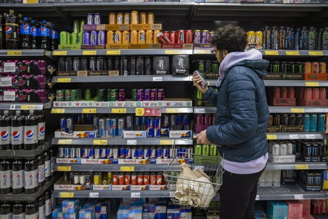 Archivo - Un joven mira la sección de bebidas energéticas en el supermercado.