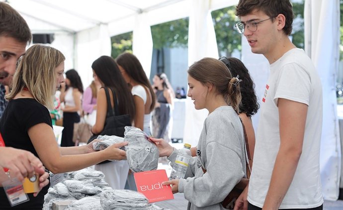 Nuevo alumnado de la UPNA recogiendo camisetas en uno de los puestos informativos de la jornada de bienvenida